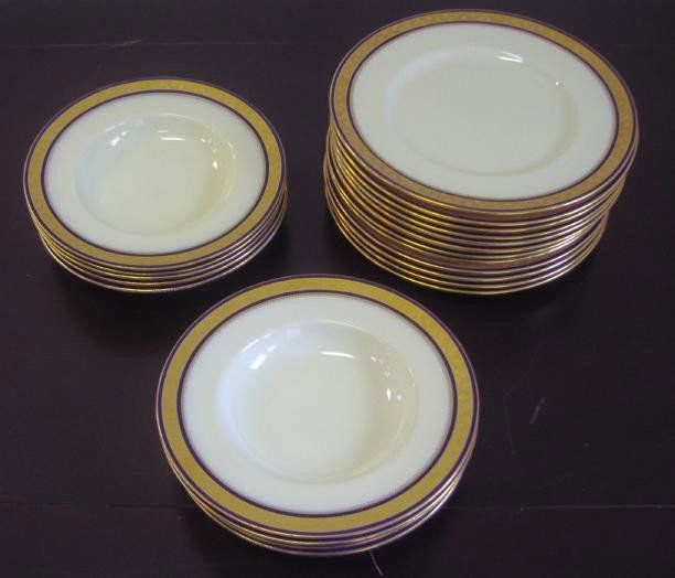 Minton for Tiffany, Gold & Cobalt Plates & Bowls: Twelve porcelain plates and nine shallow soup bowls by Minton and made for Tiffany & Co. The pieces have two bands of cobalt blue surrounding a band of gold with florals. The stock number is H2941. Th