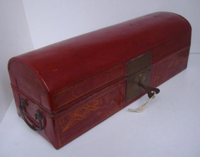 Chinese Red Pig-Skin Document Box: The domed covered box is decorated with two panels of a village scene plus a floral/urn motif and measures 16" long, 5.5" tall and 5" wide. Has brass handles, lock and key.