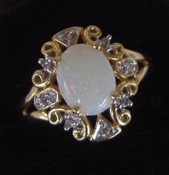 White Opal & Diamond Ring set in 14K Gold: Center white opal stone, surrounded by eight small diamonds set in 14K Gold. Ring size 7.