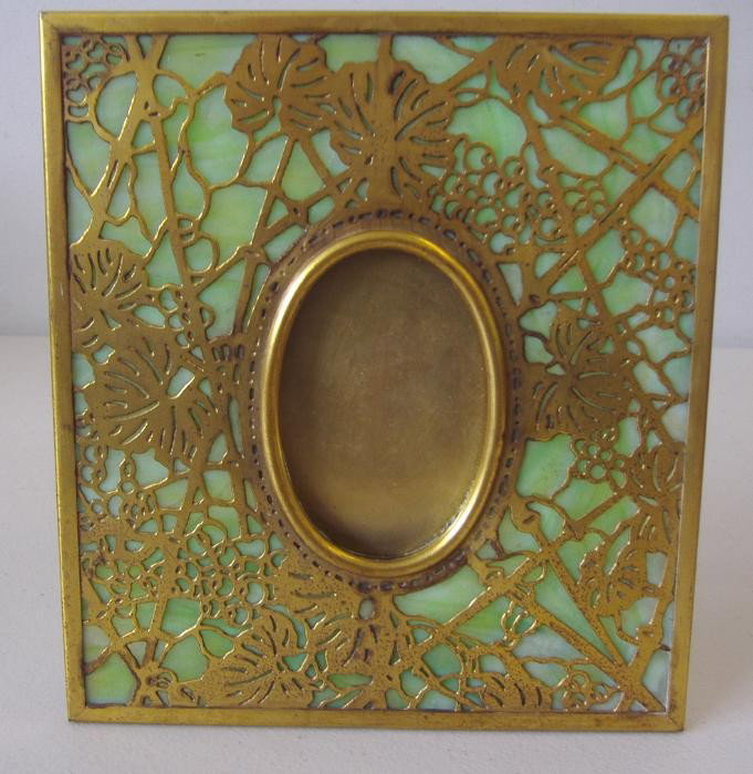 Tiffany Studios Grapevine Frame, Bronze & Glass: Tiffany studios dore bronze picture frame with light green slag glass. The overall measurement: 6.75" x 6-1/8". The oval portion measures 3" x 2". The back of the frame is signed Tiffany Studios, New 