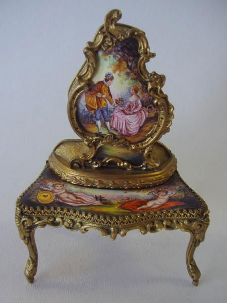 Viennese Enamel Music Box Dressing Table: c.1900, Viennese / Austrian enamel miniature furniture form musical (non-opening), dressing table cabinet. The gilt metal and enamel piece is decorated with a courting couple and putti in a pastoral s