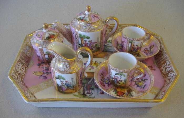 Helen Wolfsohn Crown Dresden Miniature Tea Set: Miniature porcelain tea set comprised of a tray, teapot, covered sugar bowl, cream pitcher and two cups with saucers. The tray measures 8" x 6.5" and 1" high. The tray bearing the Crown Dresden mark o