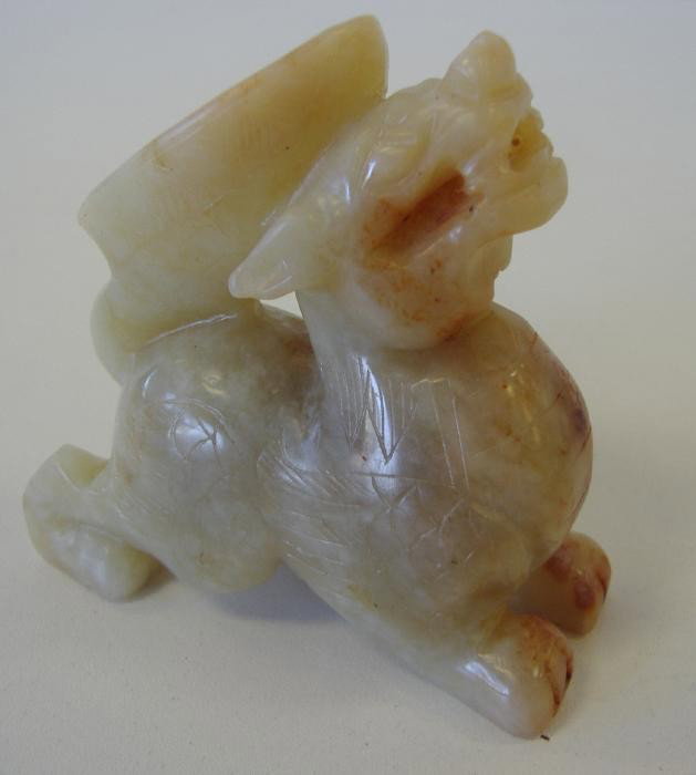 Chinese Jade Carving of a Foo Dog w/Libation Cup: Etched jade carving depicting a foo dog/lion with a libation cup on his back. Measures 2.5" high and 2-5/8" long.