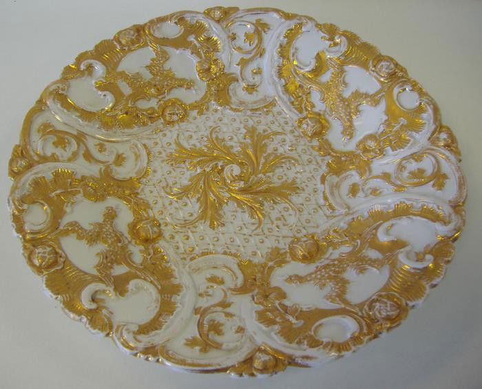 Meissen Porcelain Gilt Decorated Platter: Decorated with birds in flight surrounded by floral swags. The gilt-decorated porcelain plate measures 10.75" in diameter and 1.5" high. Signed with the Meissen crossed swords mark underfoot.