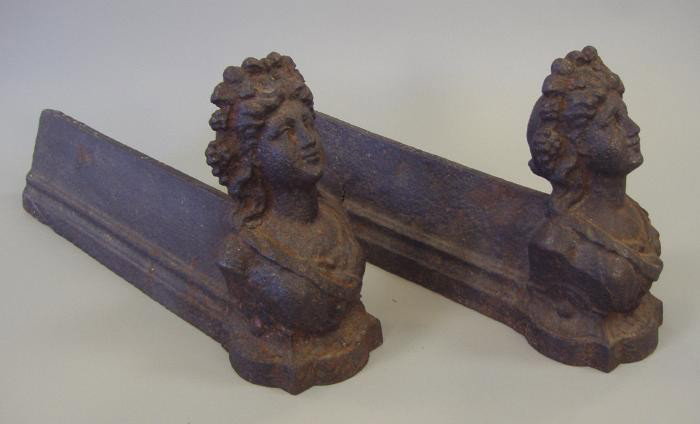 Victorian Cast Iron Fire Dogs Andirons of Females: Cast iron andirons or fire dogs each depicting a female. Measures 7" high and 14" long. NOTE: one andiron with partial crack, (see photos).