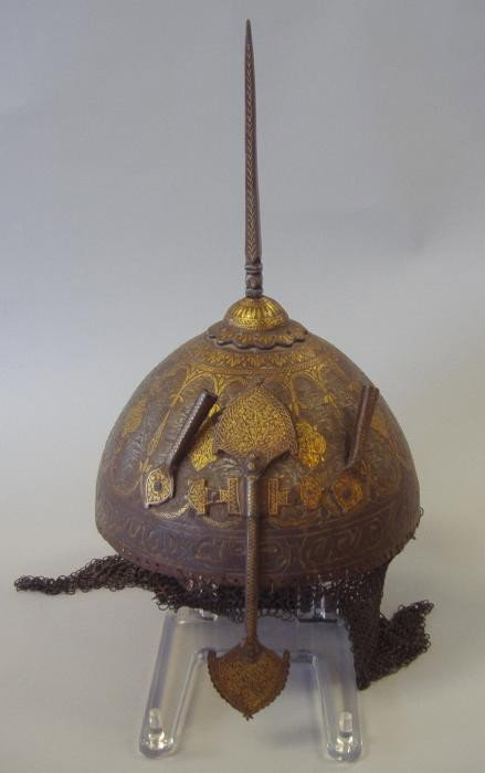 18thc Indo-Persian Islamic Gilt Metal Helmet: The gilt decorated Indo-Persian Islamic helmet is surmounted by a finial. Two plume-holders flank each side of the nose guard. Chain-link mesh attached to rear and sides, some losses to the mesh. See 
