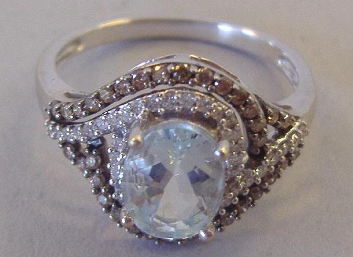 Aqua Marine & Diamond Ring set in 14K Gold: Oval 1.25 carat aqua marine surrounded by chocolate and white diamonds set in 14K white gold. Overall weight 3.2 grams. Ring size 7.