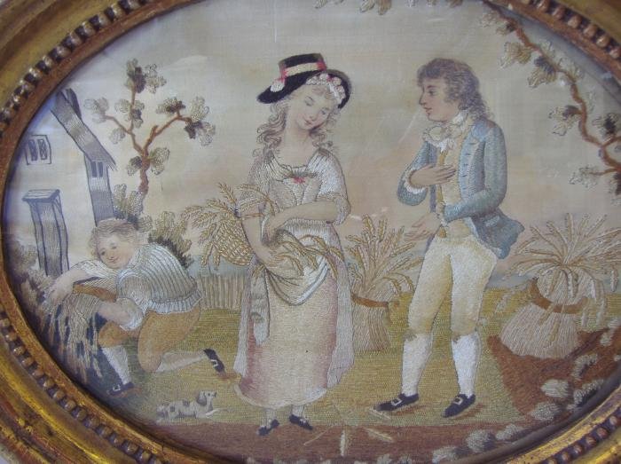 19thc English Needlework on Silk "Young Love": 19thc English framed oval needlework on silk of a young courting couple and her dog. A young male gardener looks on. Image measures 11" x 8.5". Framed measurement 11" x 14".