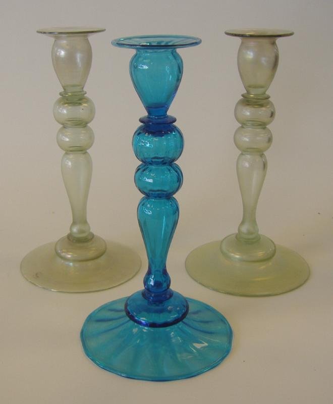 3 Steuben Celeste Blue & Green Candlestick Holders: Two light green candlestick holders with iridescent shades of pink and yellow, together with a celeste blue candlestick. Each measuring approximately 10" high. These are identified as No 2596 from Gar