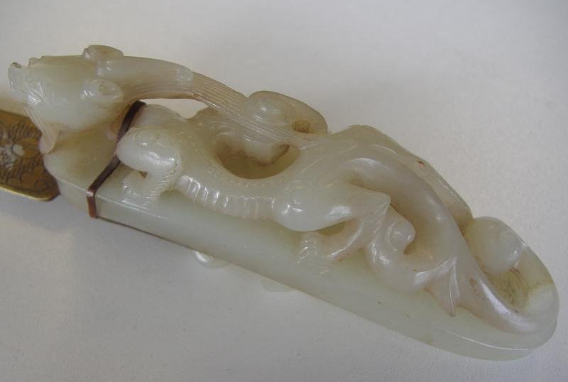 Chinese White Nephrite Jade Dragon Belt Buckle: Chinese carved white nephrite jade belt buckle in the form of a dragon. The buckle measures 3.75" long, 7/8" wide and 1.5" high. The buckle has a brass band, which is attached to an etched brass lette