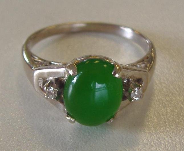 Jade & Diamond Ring set in 10K White Gold: Translucent jade ring flanked on each side with a diamond. 10K white gold filigree setting. The jade measures approximately 8mm x 6mm. Ring size 6.5.