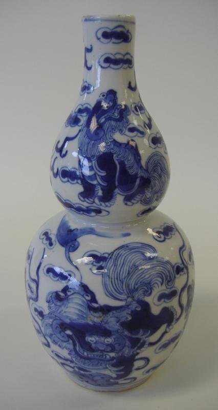 Chinese Double Gourd Foo Lion Vase, Kangxi Mark: Chinese blue and white porcelain vase with Foo lion dog decoration surrounding the body. Measures 8.75" tall. Signed underfoot with the Kangxi 4-character mark.