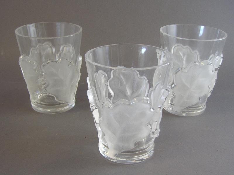 3 Lalique Whiskey Tumblers w/ Oak Leaf Motif: Three Lalique France high-ball tumblers with a frosted glass oak leaf motif. The tumblers measure 4.75" high and 3-5/8" in diameter. NOTE: one glass with small chip to inside rim.