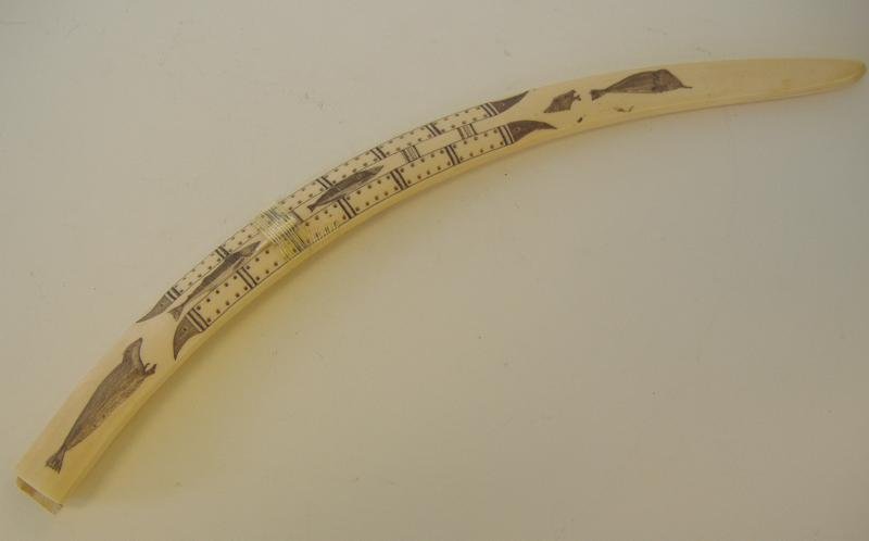 Carved Inuit Walrus Ivory Scrimshaw Cribbage Board: Vintage Inuit carved walrus ivory scrimshaw cribbage board. Decorated with a seal and fish motif on one side and a fisherman in his kayak on the other. Measures 22" long. Has one peg, missing end cap.