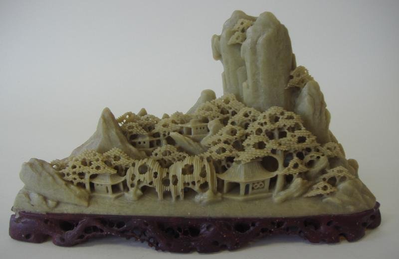 Chinese Soapstone Carving, Mountain Village: Early 20thc Chinese soapstone intricate carving depicting a village in a mountain setting. Rests on a carved brown soapstone stand. Measures 5.75" high, 10.5" long and 3" deep.