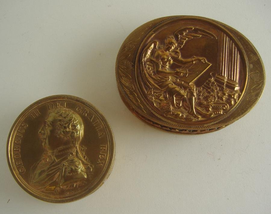 Two Brass Snuff Boxes, George III & Mythological: Two brass snuff boxes, one a commemorative box depicting George III, measuring 2-1/8" in diameter and 1" high. Together with a Greek mythological female embossed on the lid. Measures 3.25" x 2.5" x .7