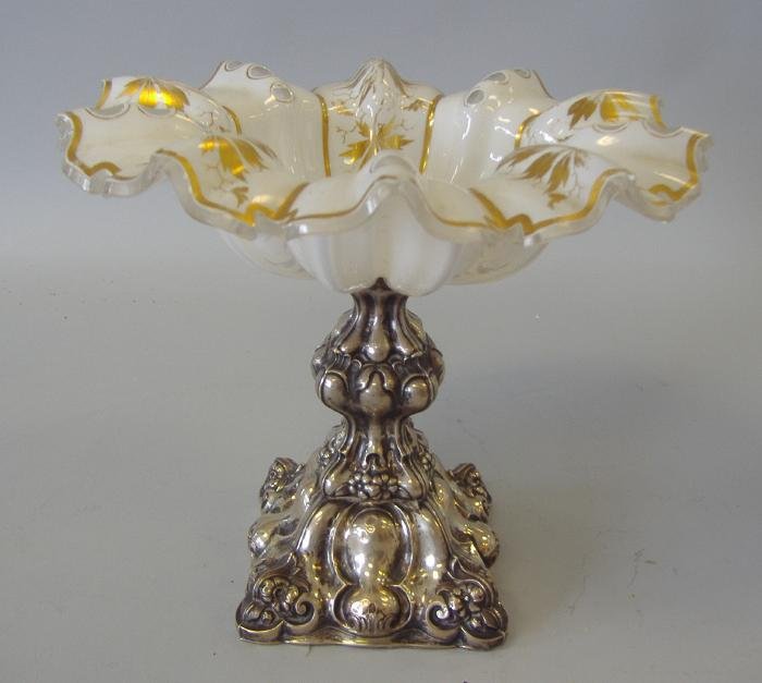 Victorian Sterling & Gilt Glass Compote: Gilt-decorated glass compote mounted on a sterling base with embossed floral and leaf decoration. Unsigned. Measures 9.5" in diameter and 8" high. NOTE: some chips to edges.