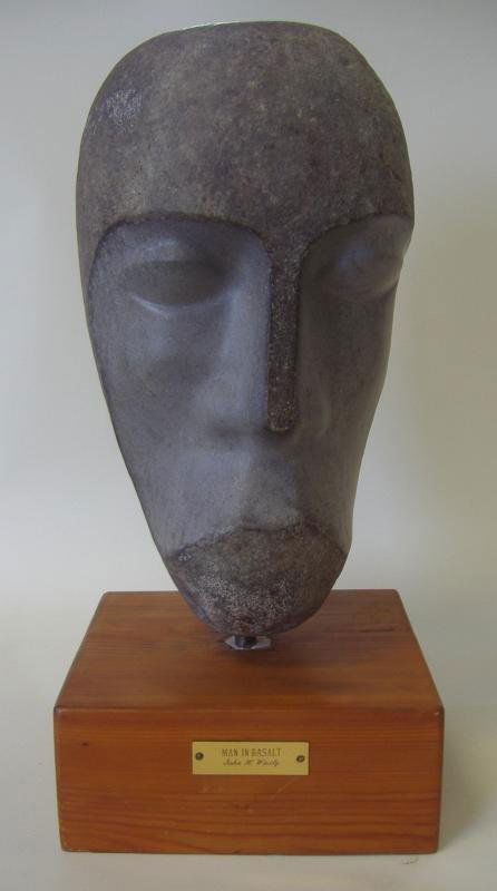 JOHN WISELY (1908-) Man in Basalt, African Male: Stone sculpture, by John Henry Wisely. Depicts the head of an African male. Brass plaque with the title "Man in Basalt". Signed with the artist's cipher on the back of the sculpture and dated 1968. Ov
