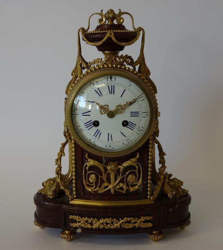 French Rouge Griotte Marble Mantel Clock: Louis XVI style rouge griotte marble and ormolu mantel clock. Painted enamel dial. Measures 14" high and 11" x 4" at the base. NOTE: lacking rear door, pendulum and key. No guarantee of working order 