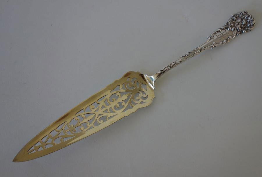Sterling Pastry Server, La Reine, Reed & Barton: Sterling silver pastry server by Reed & Barton in the 1893 La Reine pattern. Gold wash and pierced triangular server measuring 9.75" long. Weighs 1.63 troy oz. Stylized monogram W on handle.