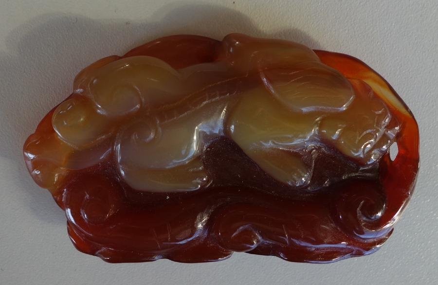 Chinese Carnelian Dragon Pendant: Chinese carnelian carving depicting a dragon on a fungus. Measures 2" long x 1.5" high.
