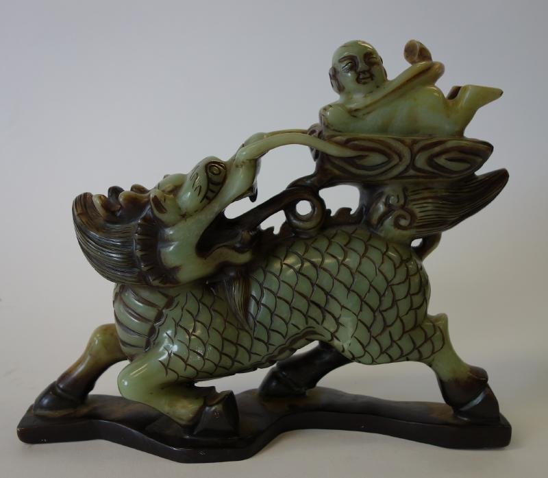 Asian Hardstone Beast and Male Figure: An Asian hardstone etched carving depicting a young male riding a mythological beast. Measures 8" high, 10" long and 3" wide. NOTE: chip to tooth. See photos.