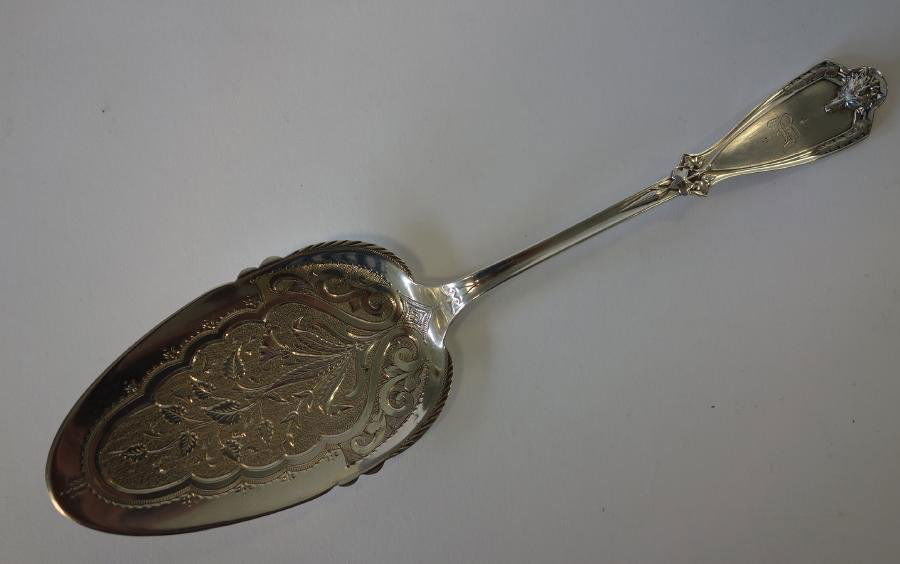 Coin Silver Pastry Server, F.A. Bunnell: A coin silver pastry or pie server. Marks for F. A. Bunnell & Co., Syracuse, New York. c. 1850s. Embossed fox on the handle, chased floral and swag motif. Measures 10.25" long. Stylized monogram B. We