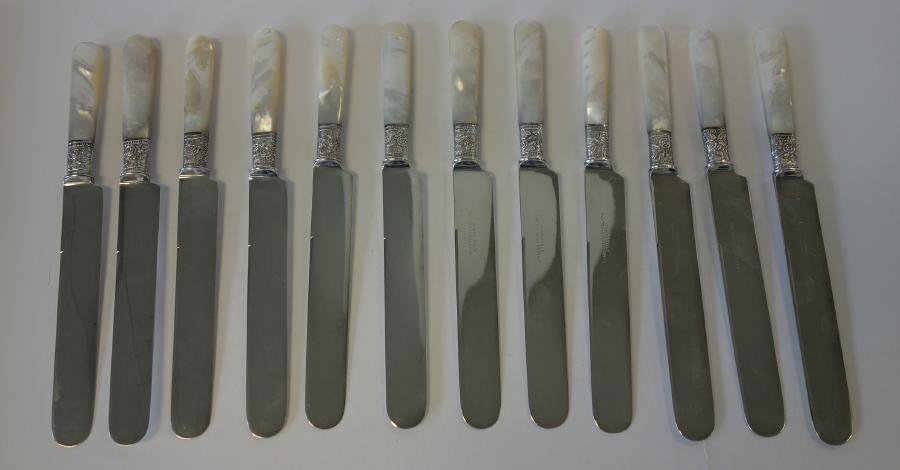 12 Mother of Pearl & Sterling Knives: A set of 12 mother of pearl handled knives with floral embossed sterling ferrules. The blades marked Landers Frary & Clark, Aetna Works. Each measuring 8.5" long.