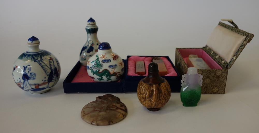 Chinese Snuff Bottles & Soapstone Chops: 5 Chinese snuff bottles. Comprised of 3 porcelain enamel painted bottles, a carved walnut and a Peking glass bottle. Together with three stone seal chops and a soapstone carving of a money bag.