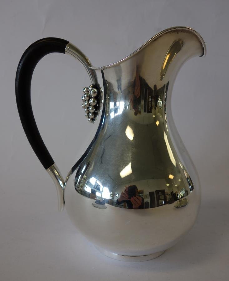 E. Dragsted Sterling Water Pitcher, Denmark: A Danish sterling silver water pitcher by E. Dragsted. Applied grapes under the sterling and ebonized wood handle. Signed underfoot. Measures 8" high. Weighs 19.14 troy oz.