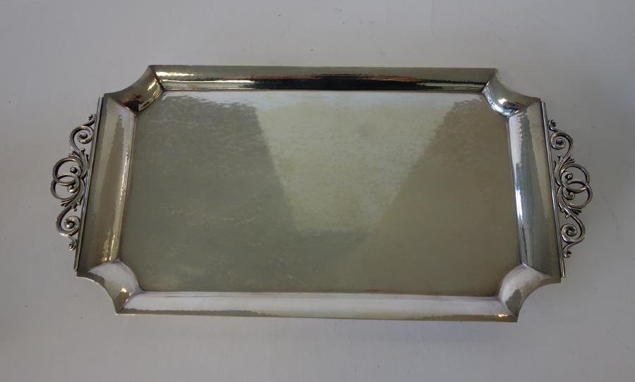 Georg Jensen, Johan Rohde Sterling Tray: A sterling silver tray by Georg Jensen. Designed by Johan Rohde (1856-1935). Hand-hammered tray with scroll formed handles, resting on bun feet. Measures 12" x 5-7/8" x 5/8" high. Signed underfoot wit