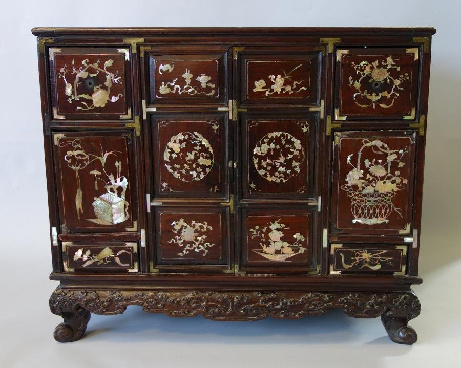 Chinese Rosewood & Mother of Pearl Cabinet Chest: A Chinese rosewood cabinet chest. The drawers and doors inlaid with mother of pearl depicting bats, florals and precious objects. The base carved with a floral cloud motif. Measures 21" high, 24.75" w