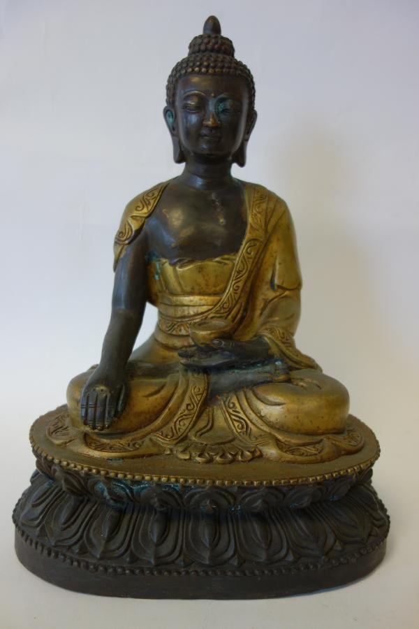 Tibetan Bronze Figure of Buddha: A Tibetan bronze figure of seated Buddha holding a cup on one hand and resting the other hand on his knee. The bronze measures 12.5" high and 9" x 6" at the base.