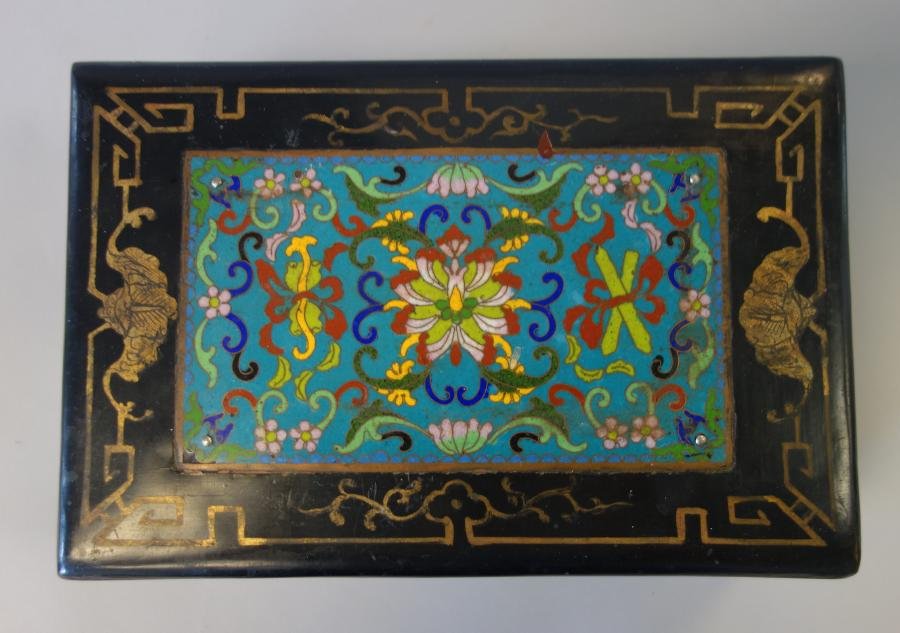 Chinese Lacquer & Cloisonne Box: A Chinese wood and black lacquer box inset with a cloisonne enamel panel. The box is gilt decorated with flowers and bats within a geometric motif. Measures 9.5" wide, 6.25" deep and 3-3/8" high.