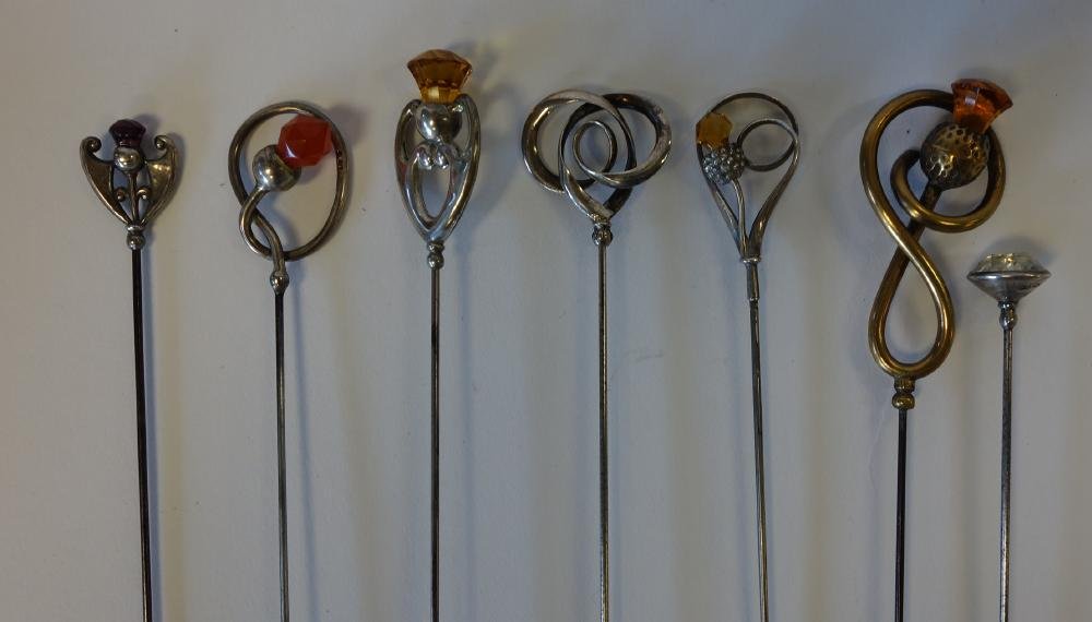 7 Charles Horner Sterling & Thistle Motif Hat Pins: Seven hat pins. Six sterling pins hallmarked for Chester, England, Charles Horner. Includes thistle, scroll and shield motifs. 5 of the six adorned with faceted glass stones. The seventh hat pin with