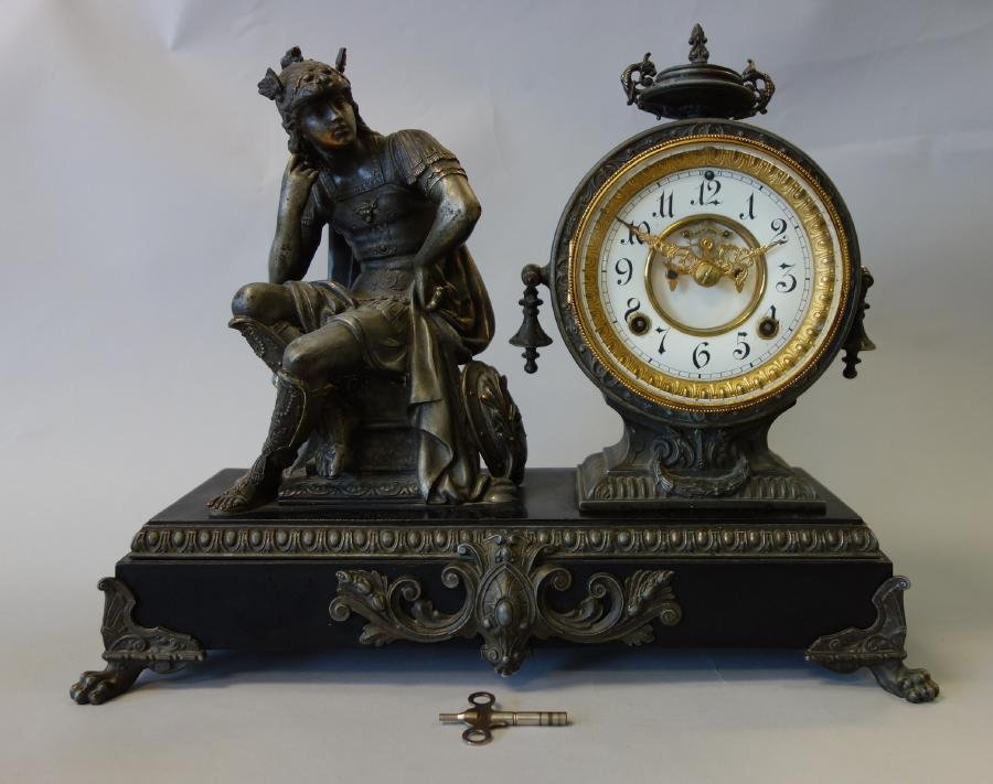 Ansonia Figural Mantel Clock, Roman Soldier: An Ansonia figural mantel clock. New York c.1890. Round clock with porcelain dial and open escapement attached next to a model of a Roman soldier, supported on a marble base resting on four paw feet.