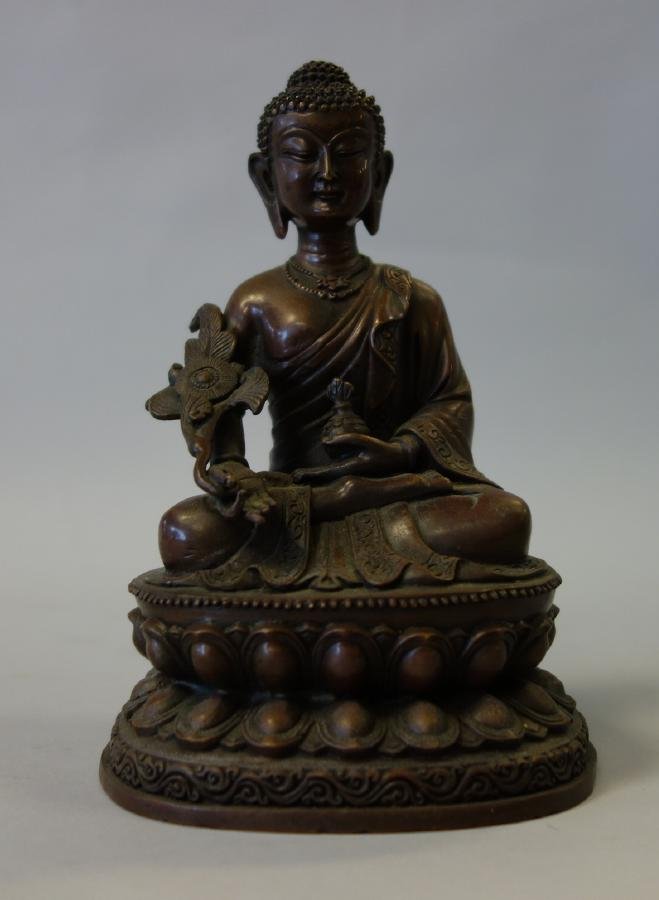 Tibetan Bronze Model of Buddha: A Tibetan or Nepal bronze model of a seated Buddha on a lotus formed base holding a vessel in one hand and a floral sceptre in the other. Measures 6-5/8" high, 4.25" wide and 3.75" deep.