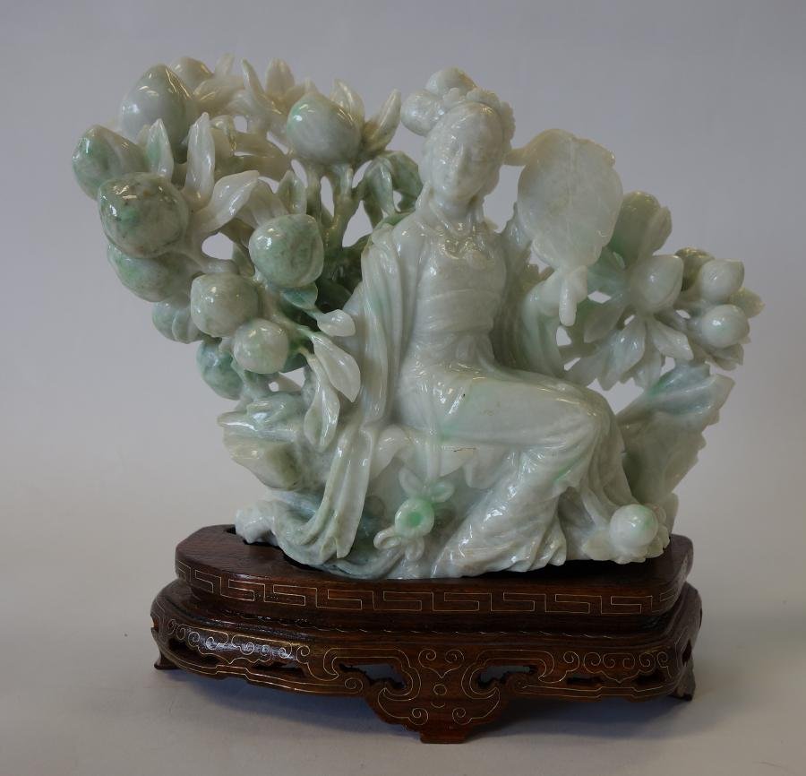 Chinese White Jade Quan Yin Carving: A Chinese jade model of female goddess Guanyin. Well carved white and light green jade depicting Quan Yin sitting and holding a large fan in a garden setting. Measures 6" high, 8.25" wide and 3" deep.
