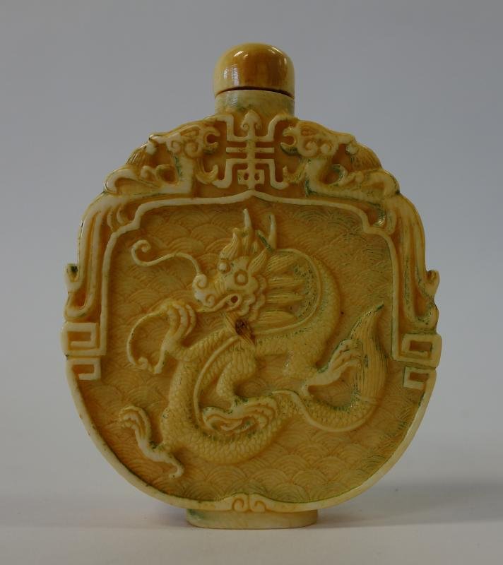 Chinese Carved Ivory Snuff Bottle, Dragon Motif: An antique Chinese ivory snuff bottle. c.1910. Flattened ovoid form. Finely carved and etched depicting dragons on the two larger sides. Opposing dragons and Chinese calligraphy at the shoulders. Meas