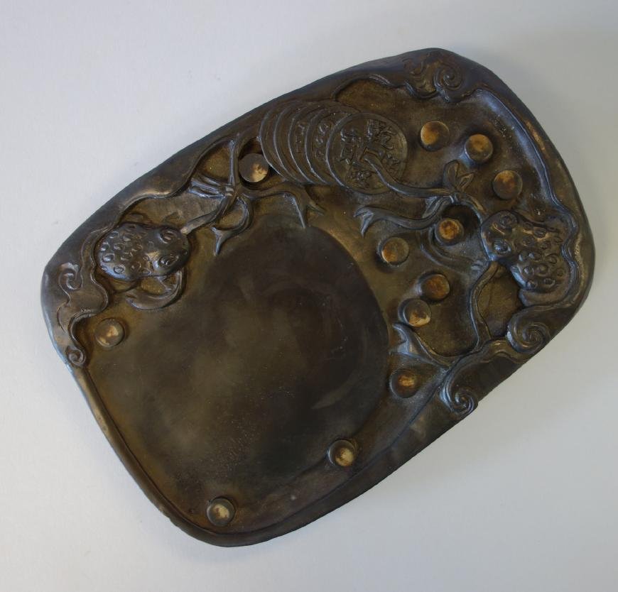 Chinese Duan Inkstone, Coins & Frogs, Signed: A Chinese duan ink stone. Well carved with raised in relief depictions of two frogs holding ribbons threading through multiple coins. Measures 8" x 5.75" x 1-1/8" high. Signed indistinctly with a 4-ch