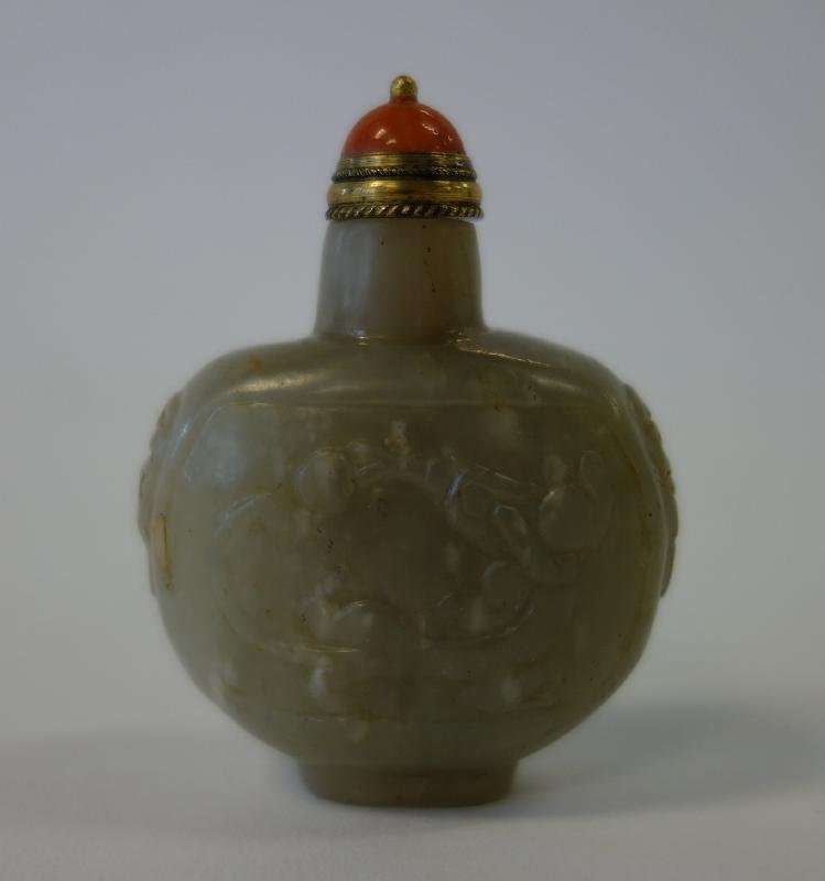 Chinese Carved White Jade Snuff Bottle: A Chinese white / celadon jade snuff bottle. Flattened ovoid form. Carved and etched on the two larger sides with dragons, the shoulders with animal faces. Measures 2.25" high to the top of the stone 