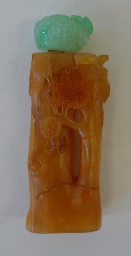 Chinese Amber & Jadeite Jade Snuff Bottle: A fine Chinese amber snuff bottle. Well carved and hollowed depicting a branched tree with flowers. Carved jadeite jade stopper cap. Measures 2.5" high.