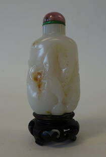 Chinese Carved White Jade Snuff Bottle: A Chinese white jade snuff bottle with hints of russet. Qing Dynasty. Well hollowed and finely carved bottle depicting a bat among fruits and foliage. Measures 3.25" high to top of rose quartz cap.