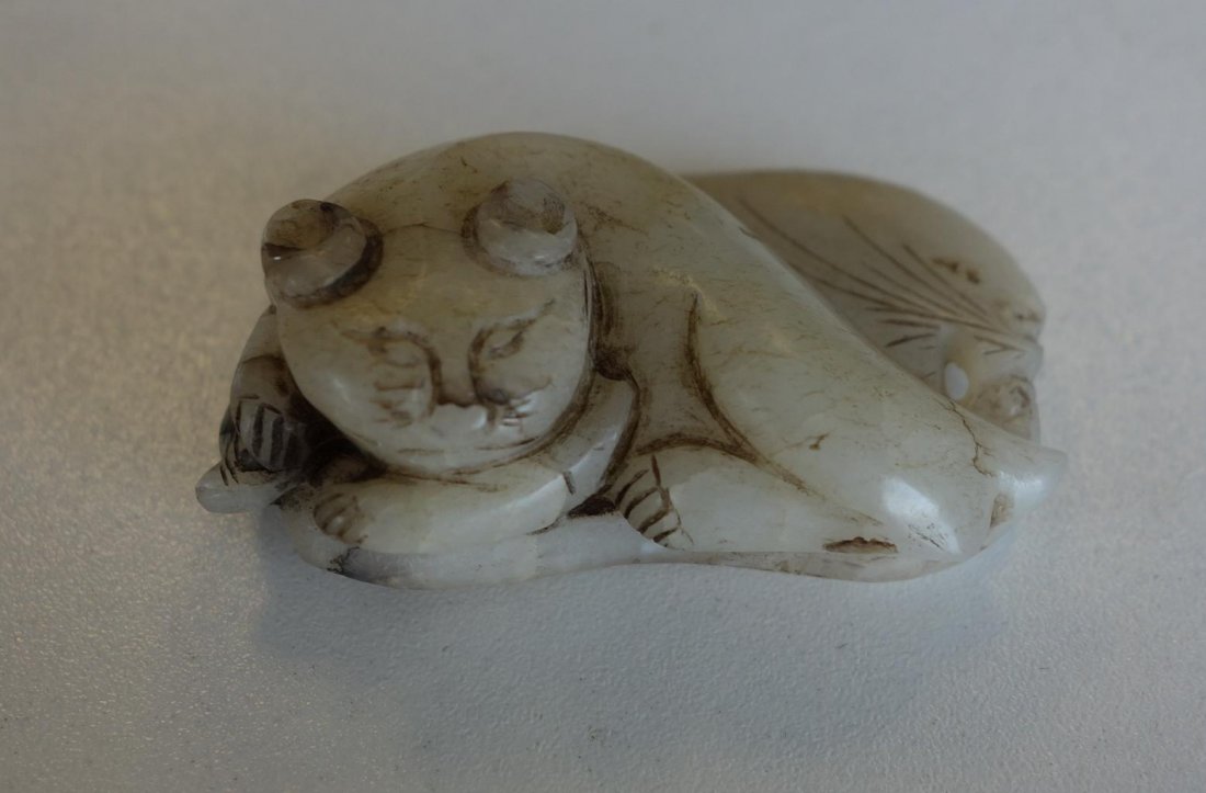 Chinese White Nephrite Jade, Resting Cat: A Chinese white nephrite jade toggle / pendant with hints of russet. Finely carved depicting a cat resting on a broad leaf. The underside of the leaf ink etched. Measures 2" x 1-3/8" x 5/8" high.