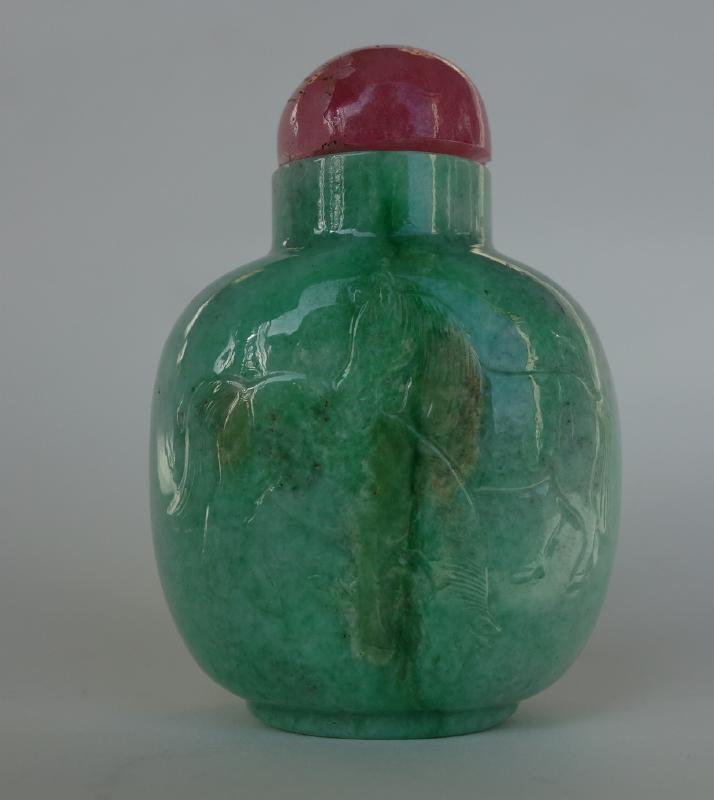 Chinese Carved Jade Snuff Bottle, Horse Motif: A Chinese jade snuff bottle. Well hollowed and finely carved in raised relief depicting recumbent and grazing horses in a pastoral setting. Measures 2.75" high to top of rose quartz cap.