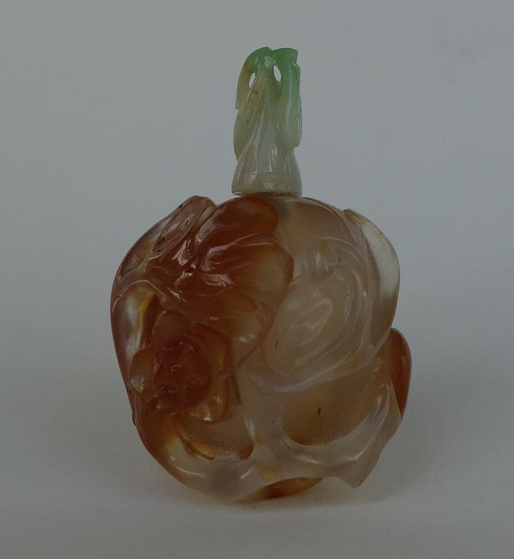 Chinese Carved Agate & Jade Snuff Bottle: A Chinese agate snuff bottle. Well hollowed and finely carved with flowers, leaves and vines entwined on the gourd formed bottle. Measures 1-7/8" high to the top of the jade leaf-formed cap, 1.25" in