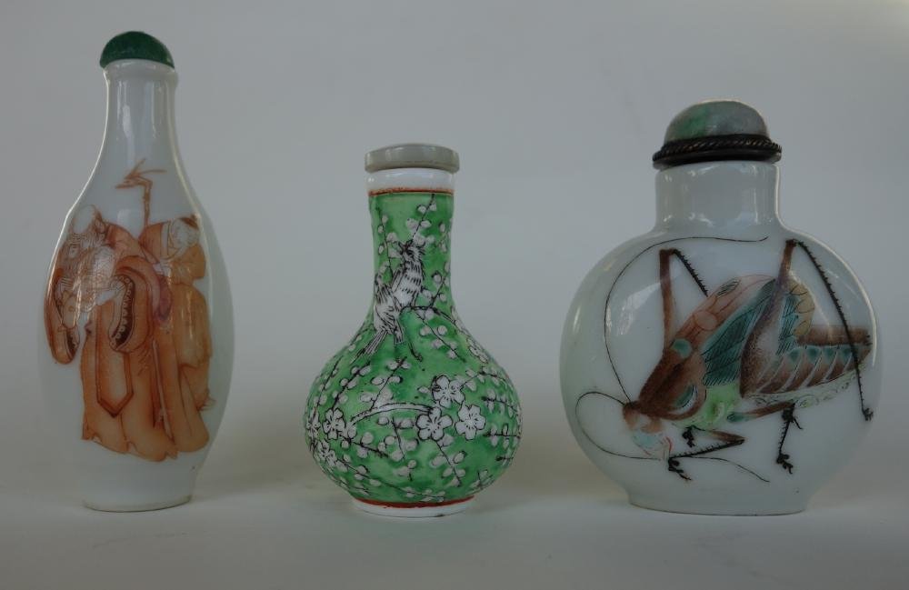 3 Chinese Porcelain & Enamel Snuff Bottles: A group of three Chinese porcelain and enameled snuff bottles. One with grasshopper motif on two sides, 2.5" high to top of jade cap, a second bottle with a depiction of a male figure holding a child,