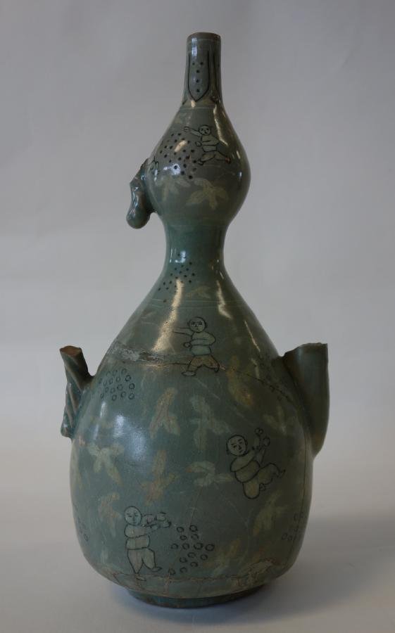 Antique Korean Celadon Double Gourd Ewer: An antique celadon glazed ewer. Formed as a double gourd. Black and white slip inlay depicting young boys playing within falling stylized leaves. Acanthus leaf decoration at the rim, NOTE: extensive r