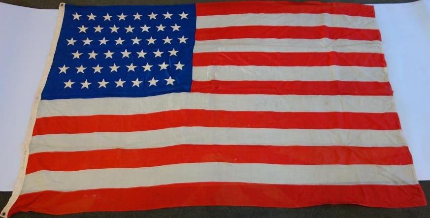 45 Star American Flag, 1896-1908, Stitched Linen: The 45 Star American Flag: Linen flag with stitched stars. The trim bears the name Alexander Ferguson. Measures 91" long, 61" high. NOTE: some scattered moth holes. The 45 star flag became the Officia