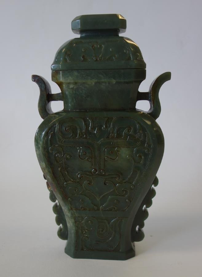 Chinese Nephrite Jade Urn Vase: A Chinese nephrite jade lidded urn / vase. Well hollowed and finely carved with stylized archaistic type masks on the two large sides, flanked on each side with carved scrolls. Red and brown veining t